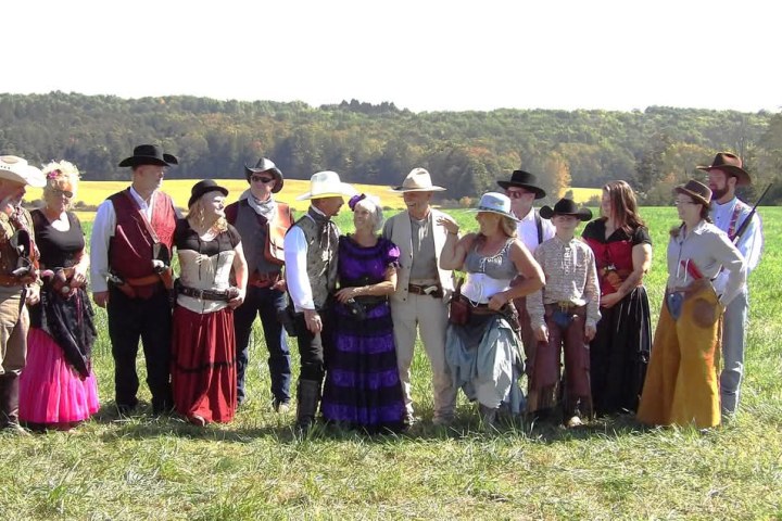 a group of people standing in a grass field posing for the camera